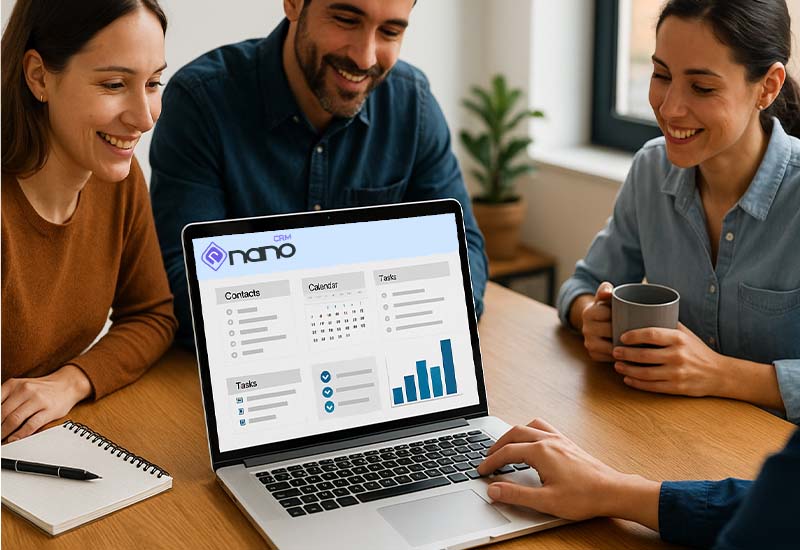 Pracovný tím pri stole používa CRM softvér na notebookoch – spolupráca, prehľad a efektivita - nanocrm